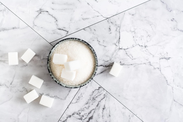 Granulated sugar and sugar cubes in a bowl on the table Top view