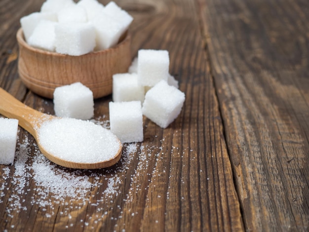 Granulated sugar on a wooden spoon closeup on an old wooden table