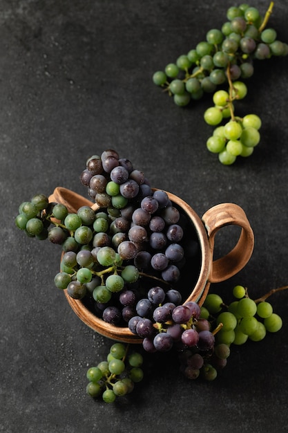 Grape bunches in ceramic cups on a gray background, top view