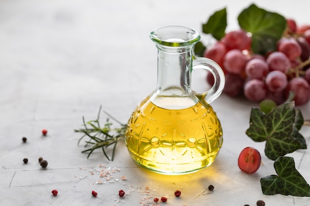 Grape seed oil in a glass bottle with a bunch of grapes.