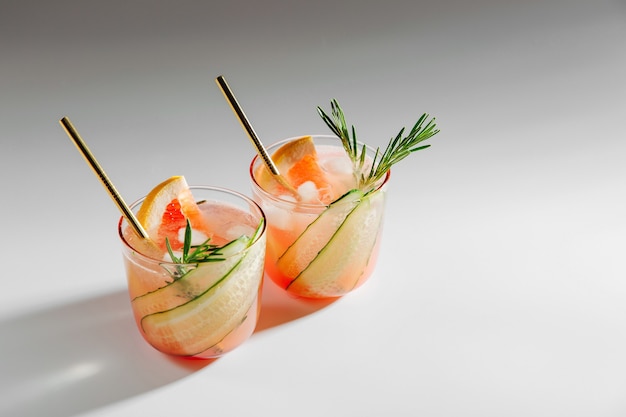 Grapefruit and Cucumber Gin Cocktail on elegant glasses on white background with shadows