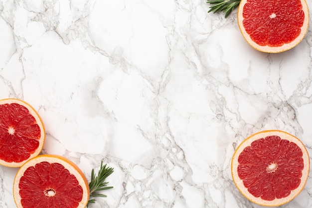 Grapefruits and rosemary on marble surface with copyspace, fruit flatlay, summer minimal and kinfolk compositon