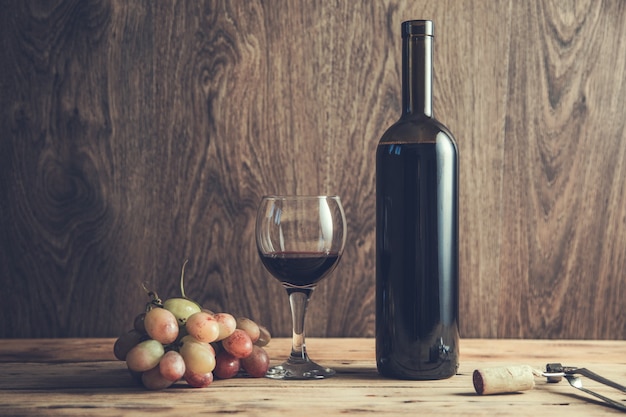 Grapes wine bottle and glass with opener on table