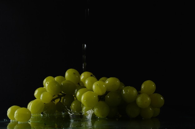 Grapes with drops of water on a black background with reflection