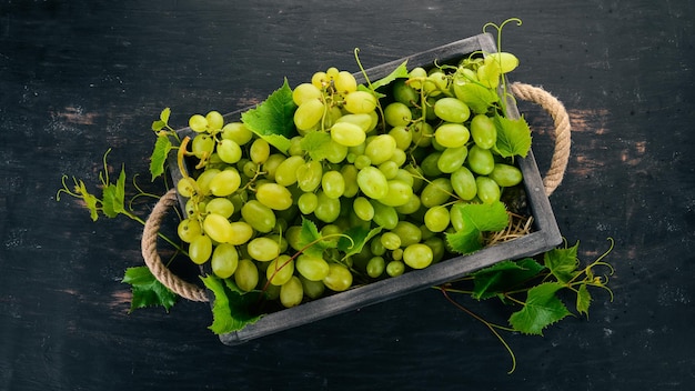 Grapes in a wooden box Leaves of grapes Top view On a black background Free space for text