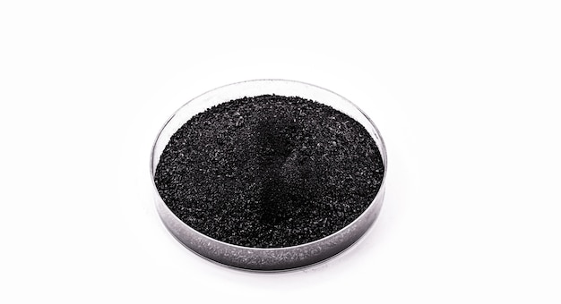 Graphite powder used in industry, black powder with isolated white surface and copy space.