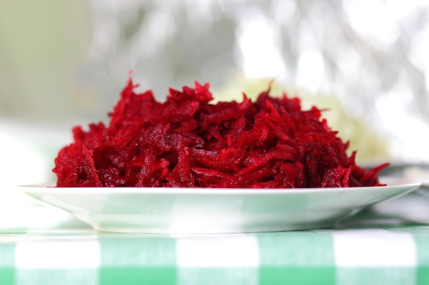 Grated red beets on a plate on a tablecloth in a home kitchen Healthy food concept Closeup