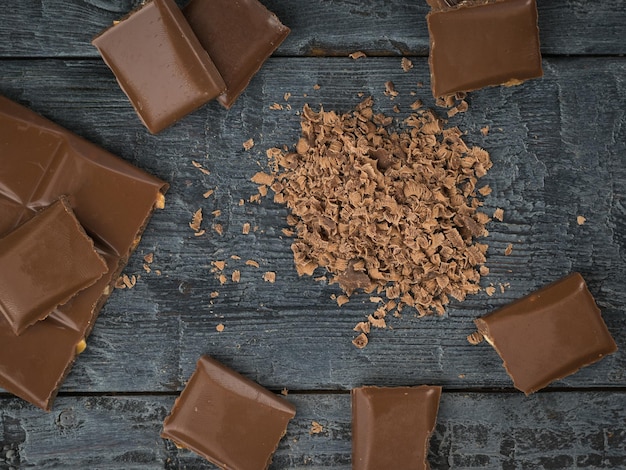 Grated and whole chocolate on a wooden table The concept of a popular sweet