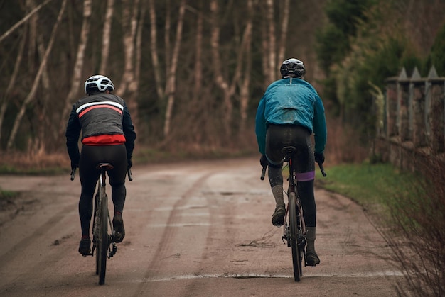 Gravel bike riding in rainy weather Bikerider from behind wearing a safety helmet Modern bicycle