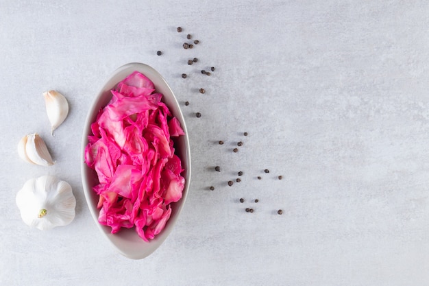 Gray bowl of chopped pickled cabbage on stone table.