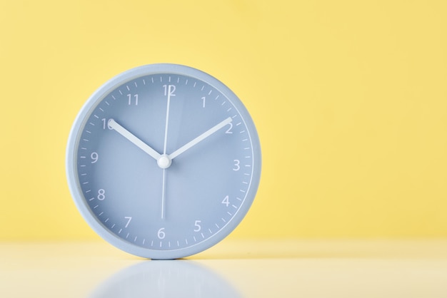 Gray classic alarm clock on a pastel yellow background with copy space