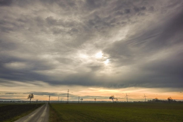 Gray clouds on the sky with sun in a flat landscape with windmills