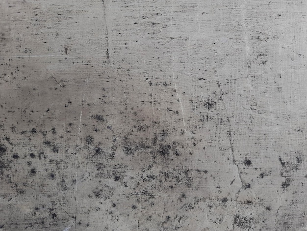 A gray concrete wall with black stains and a white spot on the bottom.