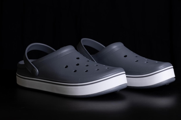 Gray crocs on a black background Rubber shoes