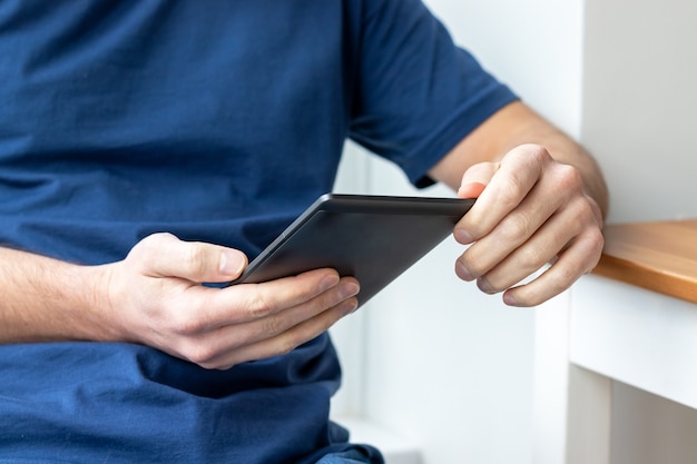 Gray e-reader electronic book in male hands.