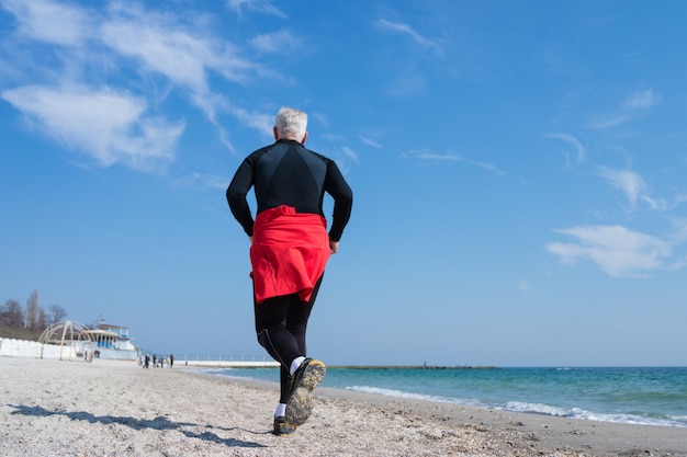 Gray-haired man running on the beach