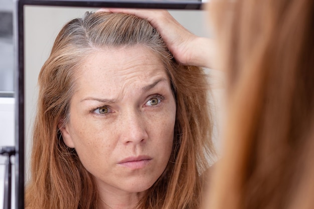 Gray haired woman looking at reflection in morror