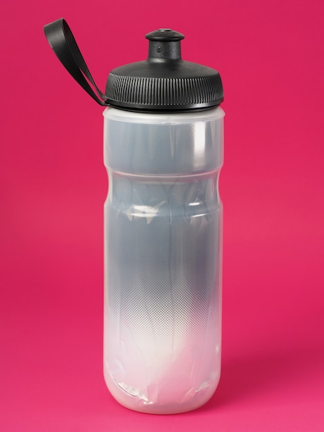 Gray insulated plastic sport bottle for cycling on red background.
