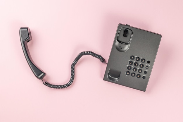 Gray landline phone on a pink background Flat lay