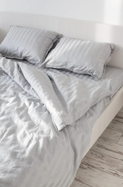 Gray linens in sunlight on  bed in  bedroom