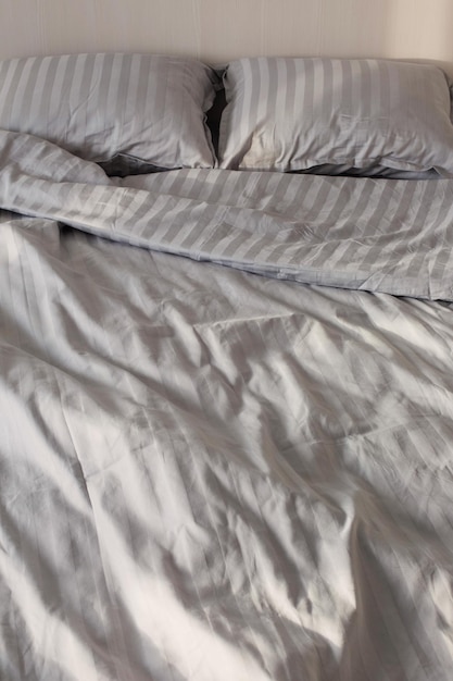 Gray linens in sunlight on  bed in  bedroom