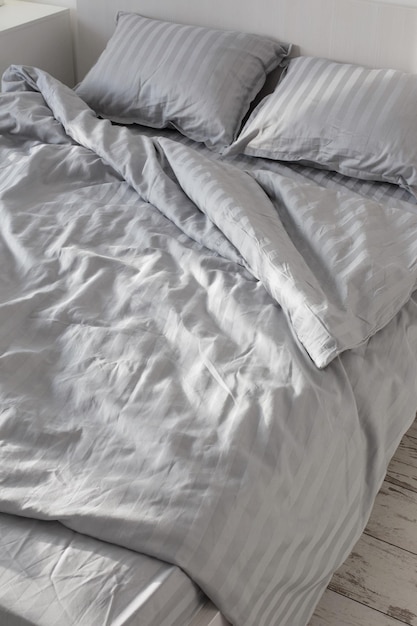 Gray linens in sunlight on bed in bedroom