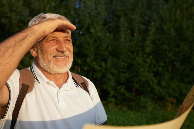 Gray male traveler squinting while looking into distance outdoors