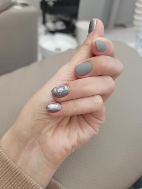 Gray manicure processed nails in salon salon coating gel polish gray manicure on white hands Russia