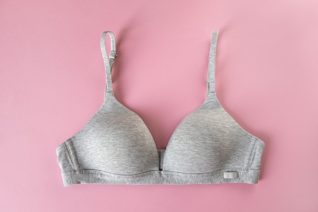 Gray organic or recycled cotton bra on pastel pink background, top view, copy space, flat lay. Concept of femininity, comfort, home clothes, underwear, natural textile, minimal style. Horizontal.