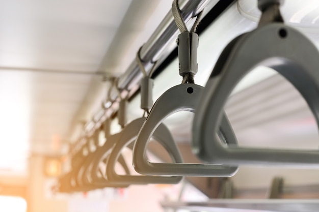 Gray plastic handles on ceiling rails for standing passengers in underground railway system MRT