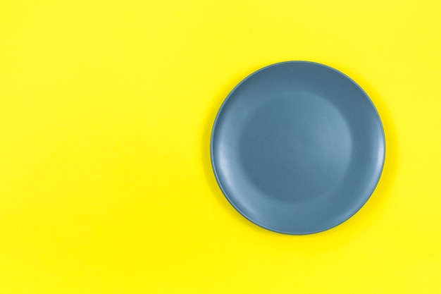 A gray plate on a bright yellow surface