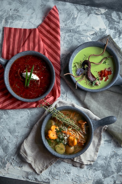 Gray plates with different soups on a gray background Plate with asparagus soup with octopus