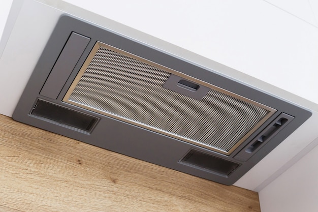 Gray range hood integrated in a white modern kitchen.