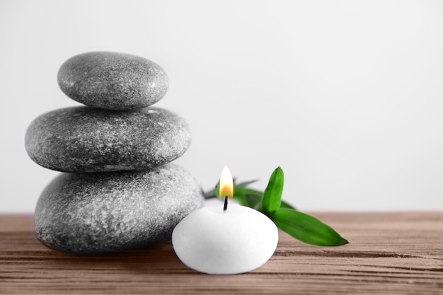 Gray spa stones with candle on light background