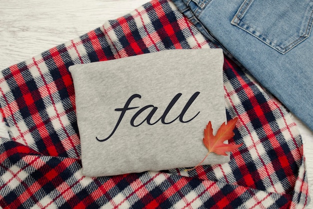 Gray sweater on checkered plaid jeans and autumn leaves Fashionable concept