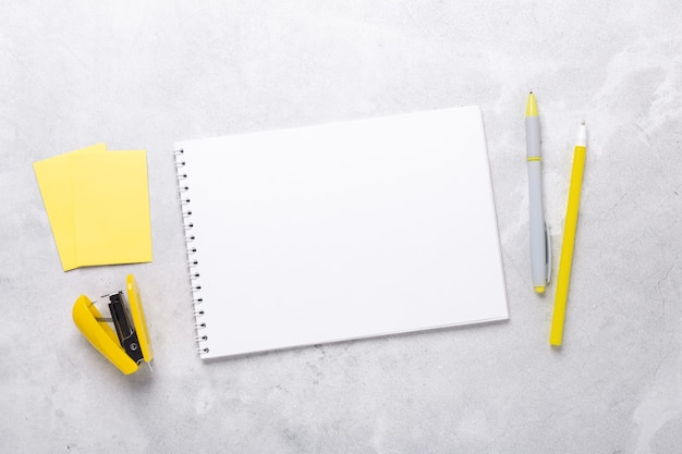 Gray workspace with notepad and yellow stationery accessories. Illuminating Yellow and Ultimate Gray, colors of the year 2021 - Image