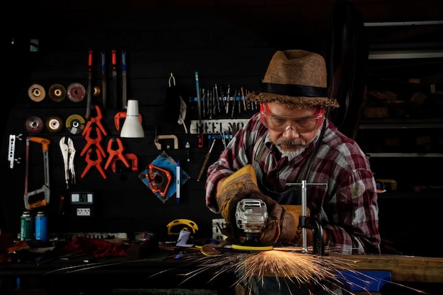 A graybearded old man a blacksmith melts redhot metal on an anvil by hand in the smithy with fireworks igniting