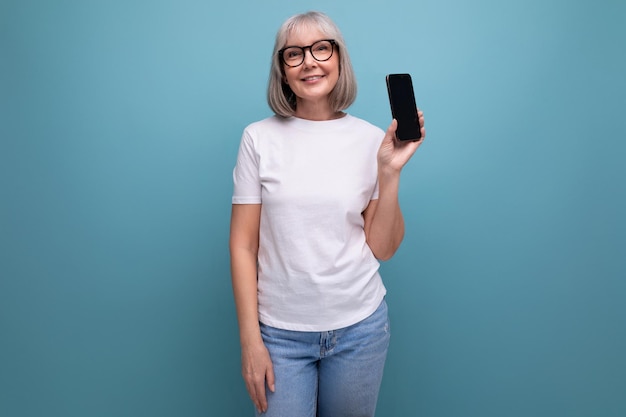 Grayhaired s woman studying digital technology smartphone on bright studio background