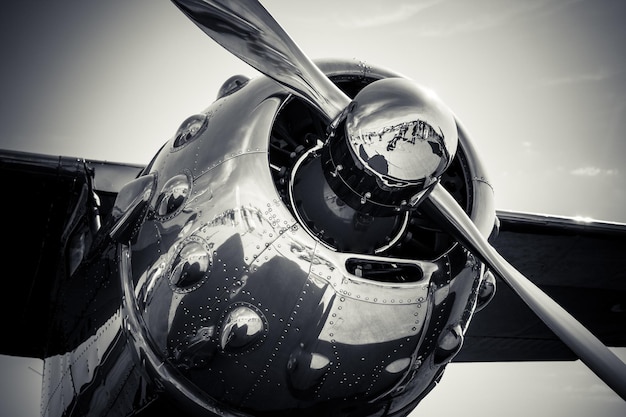 Grayscale close-up shot of a metallic aircraft propeller reflecting the environment.