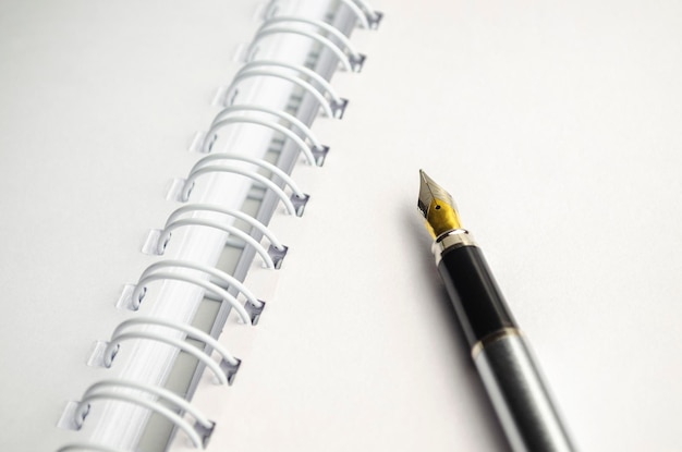 Grayscale closeup shot of a fountain pen on top of a notebook