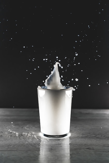 Grayscale vertical view of a white liquid splash in a glass cup