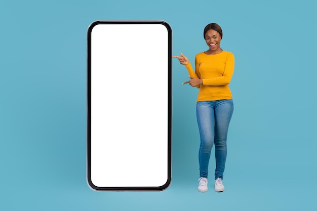 Great app beautiful african american woman pointing at big blank mobile phone