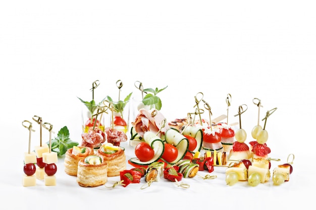 Great attractive set of canapes with vegetables, cheese, fruits, berries, salami, seafood, meat and decoration on white table