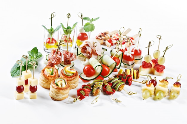 Great attractive set of canapes with vegetables, cheese, fruits, berries, salami, seafood, meat and decoration on white table