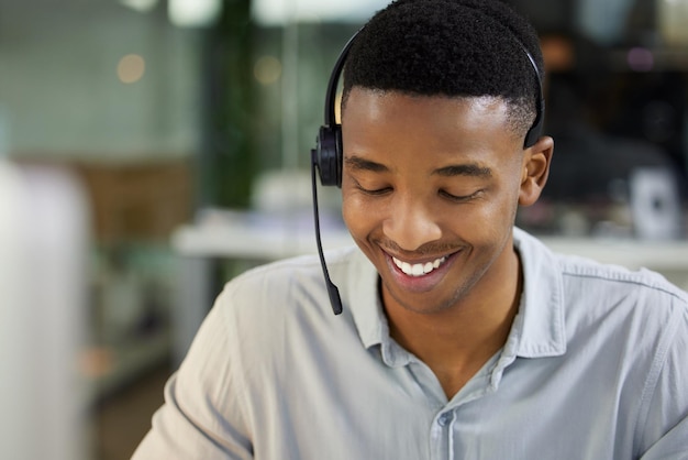 Great customer support is great business Shot of a young man using a headset and computer in a modern office