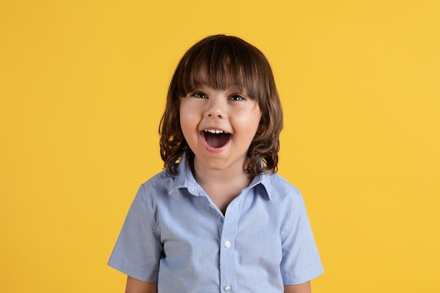 Great offer Cute little excited boy feeling surprised and amazed smiling with open mouth yellow studio background