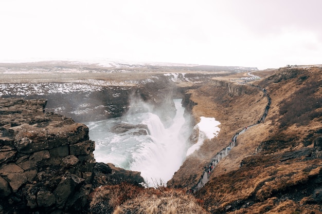 The great waterfall gullfoss in southern iceland on the golden ring tourists walk on a footpath