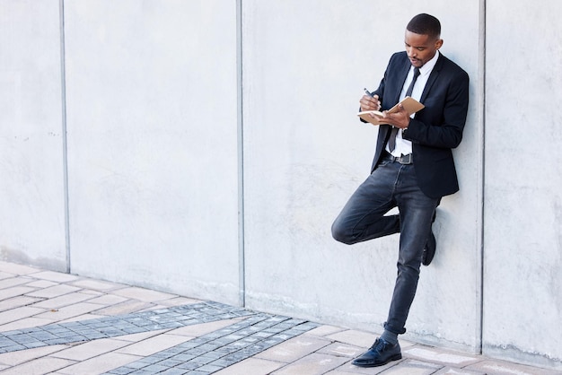 The greatest ideas come when least expected. Shot of a young businessman making notes in his notebook.