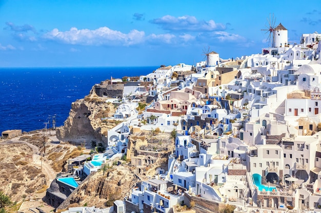 Greece vacation iconic background Famous Oia village with traditional white houses and windmills during summer sunny day Santorini island Greece