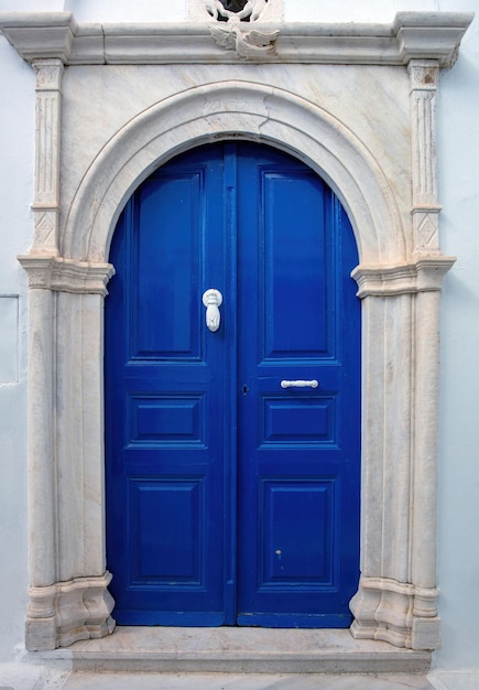 GreeceTinos island Blue home entrance door with marble arch frame on white wall